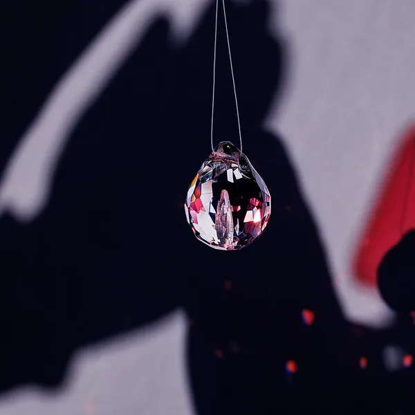 Single faceted glass teardrop pendant casting light reflections
