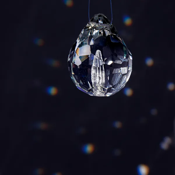 Single faceted glass teardrop pendant casting light reflections