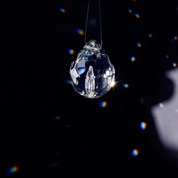 Single faceted glass teardrop pendant casting light reflections