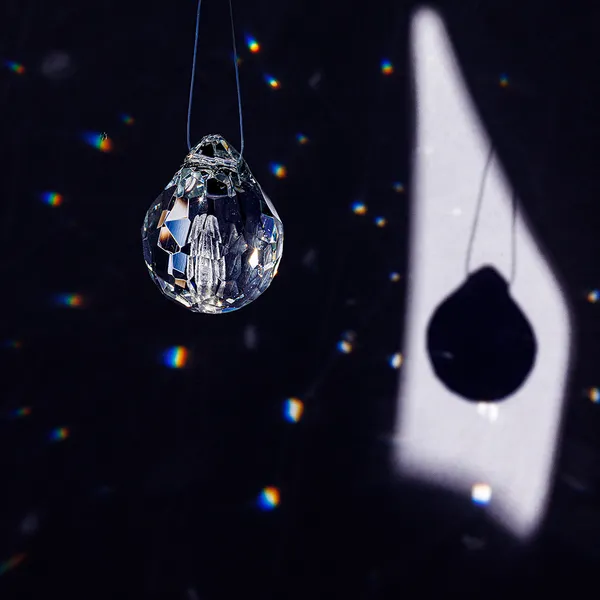 Single faceted glass teardrop pendant and its shadow projection