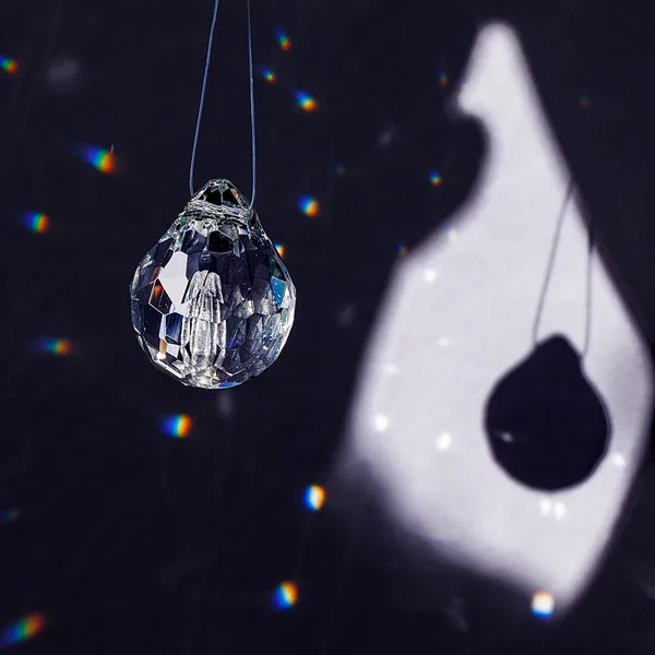Single faceted glass teardrop pendant and its shadow projection