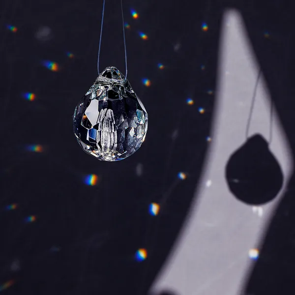 Single faceted glass teardrop pendant and its shadow projection