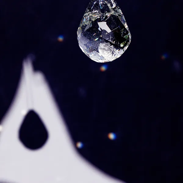 High-contrast close-up of a faceted glass teardrop pendant