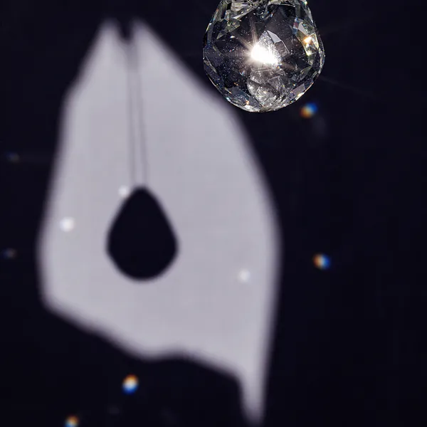 High-contrast close-up of a faceted glass teardrop pendant