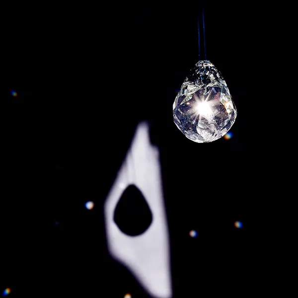 High-contrast close-up of a faceted glass teardrop pendant