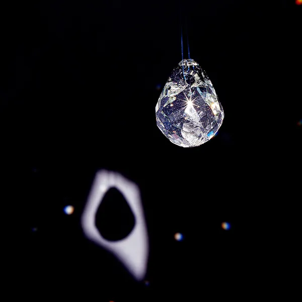 High-contrast close-up of a faceted glass teardrop pendant