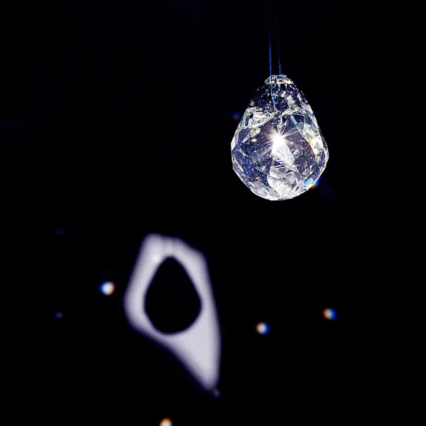 High-contrast close-up of a faceted glass teardrop pendant