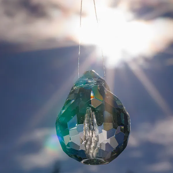Faceted glass teardrop pendant backlit by the sun
