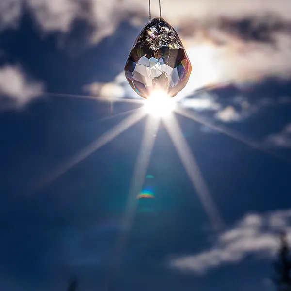 Faceted glass teardrop pendant backlit by the sun