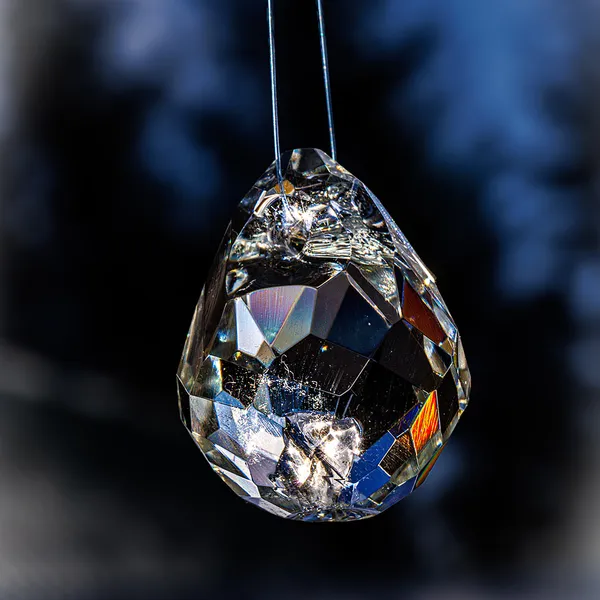 Faceted glass teardrop pendant backlit by the sun
